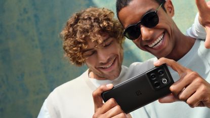 OnePlus 10T review: two men looking at a black phone smiling