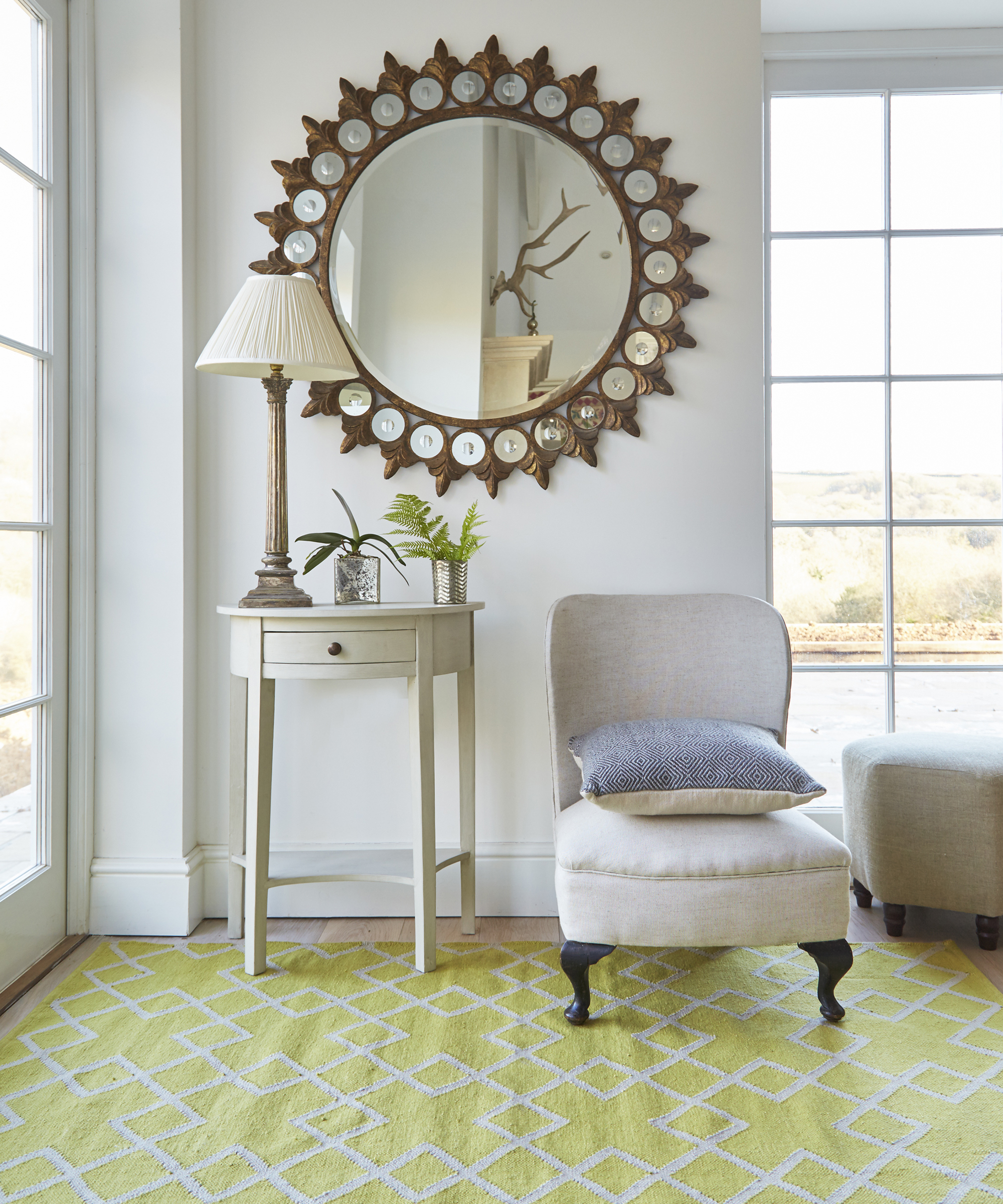 A living toom with large brass mirror and yellow rug