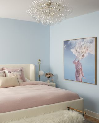 A bedroom with light blue walls and pink bedding