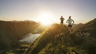 A couple running in the hills above a lake