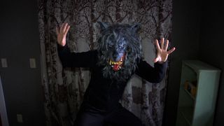 A man standing wearing a creepy wolf mask