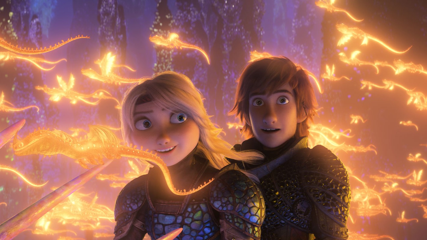 Astrid and Hiccup from the film How to Train Your Dragon: The Hidden World fly through a sea of small illuminated yellow dragons with a look of wonder.