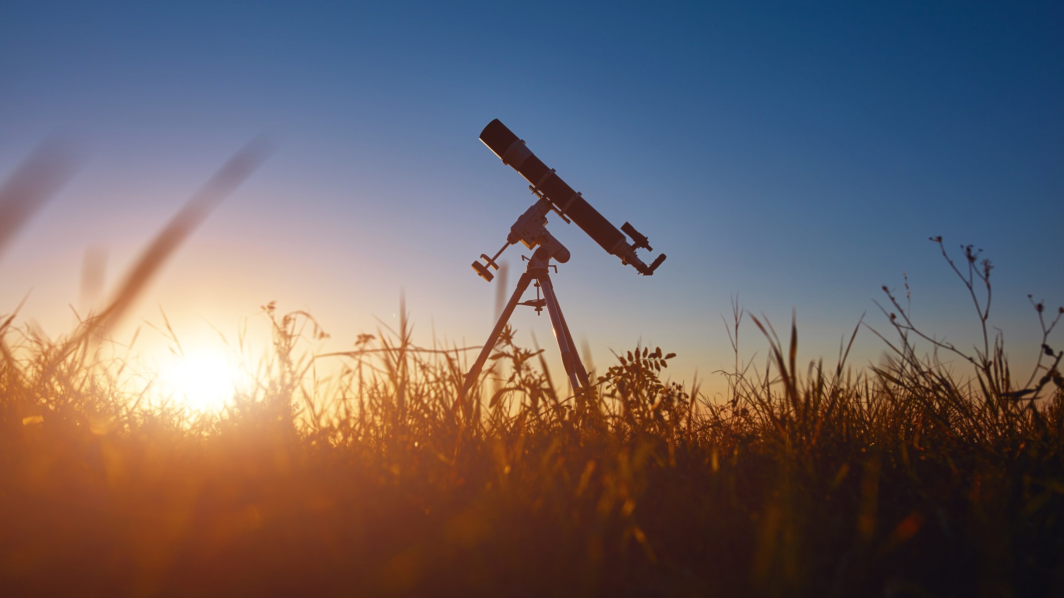 Telescope silhouette in a field with the sun setting behind.