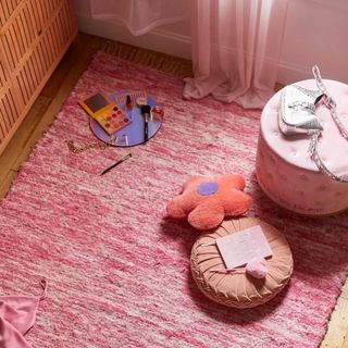 A pink shag rug sits on the floor, and is covered in pink accessories