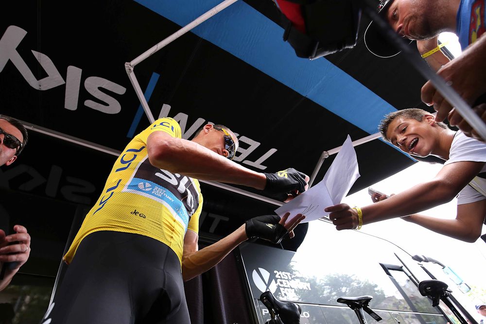 Chris Froome signs an autograph before the start of stage 14.
