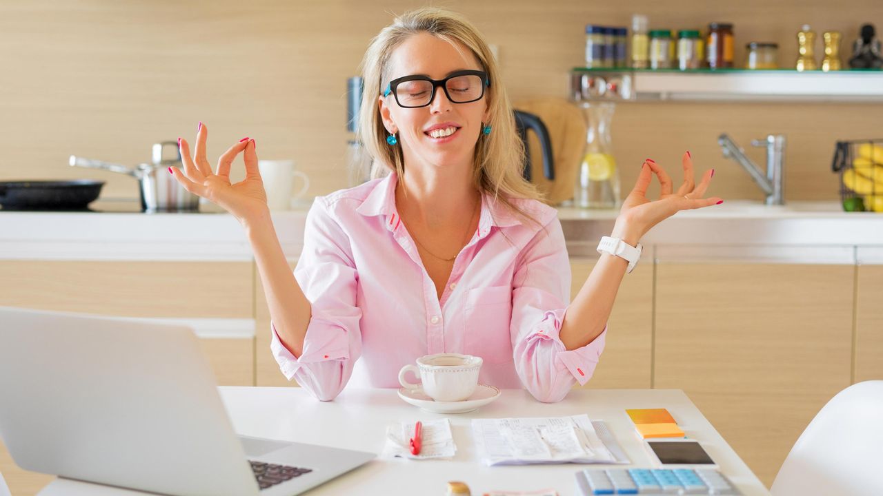 A happy woman meditates over a calculator.