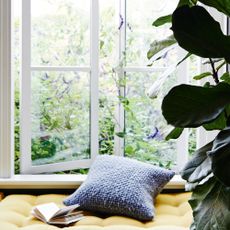 Yellow window seat beside plant and open window