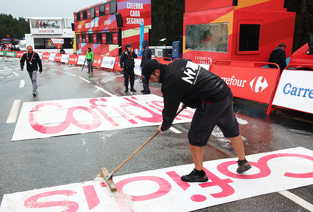 A worker tries to sweep the hail off the finish line