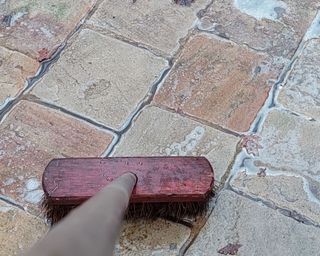 cleaning a patio with a long handled brush