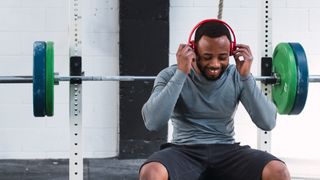 Man wearing headphones to lift weights