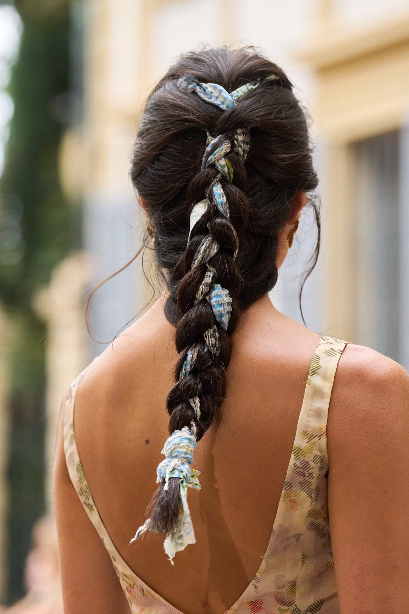 model with dark brunette hair wearing a scarf braided into her hair