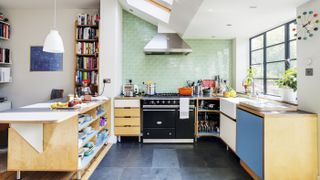 Light-filled kitchen space with plywood units, green wall tiles, range cooker and extractor