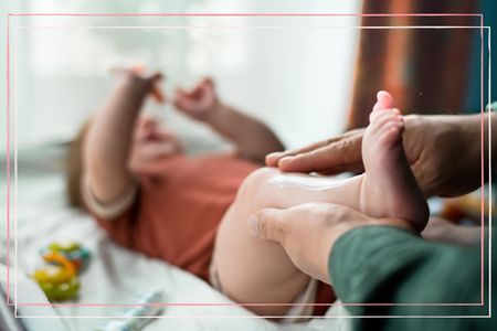 Father applying moisturizing and protective cream for baby eczema onto his child on a changing mat