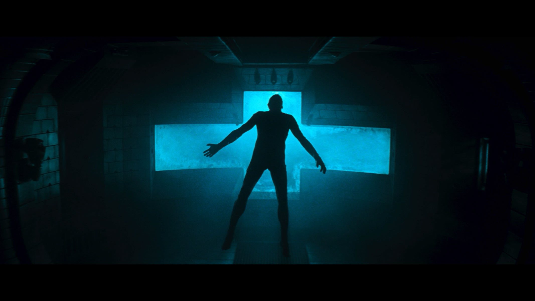 A human figures is standing with their arms and legs stretched outwards in front of a big blue plus sign.