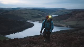 A man hiking in the dark wearing a head torch