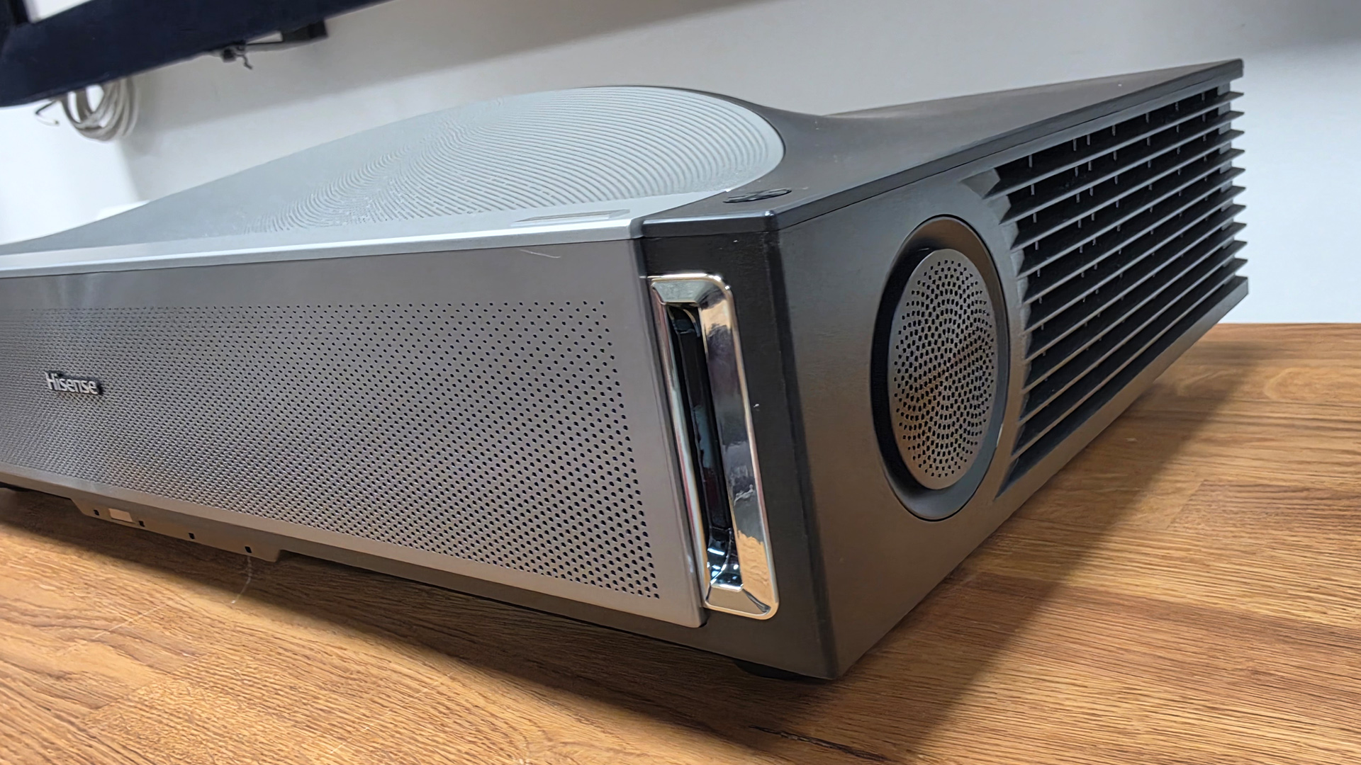 Hisense PX4 Pro UST projector on wooden AV rack side angle showing speaker grille