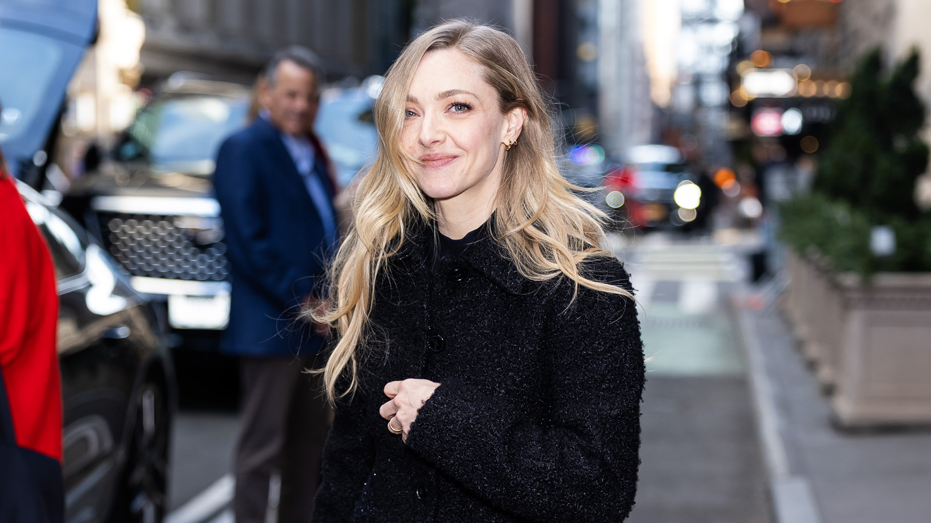 Amanda Seyfried wearing a black tweed coat, side-stripe cigarette jeans, and slingback kitten heels in NYC