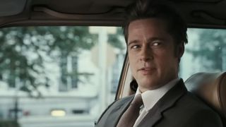 Brad Pitt trying to look tough, sitting in a car, wearing a suit