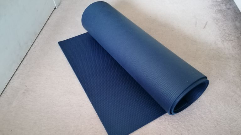 Manduka PROLite yoga mat rolled up on cream carpet