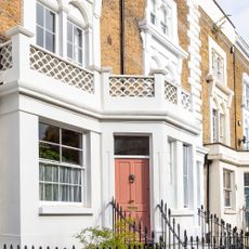 exterior of a Victorian terrace with balcony and pink painted front door