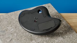 A black Logitech Ergo M575 ergonomic mouse with a teal trackball on the left side