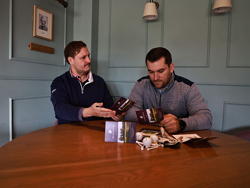 Two golfers in the clubhouse looking at their scorecards