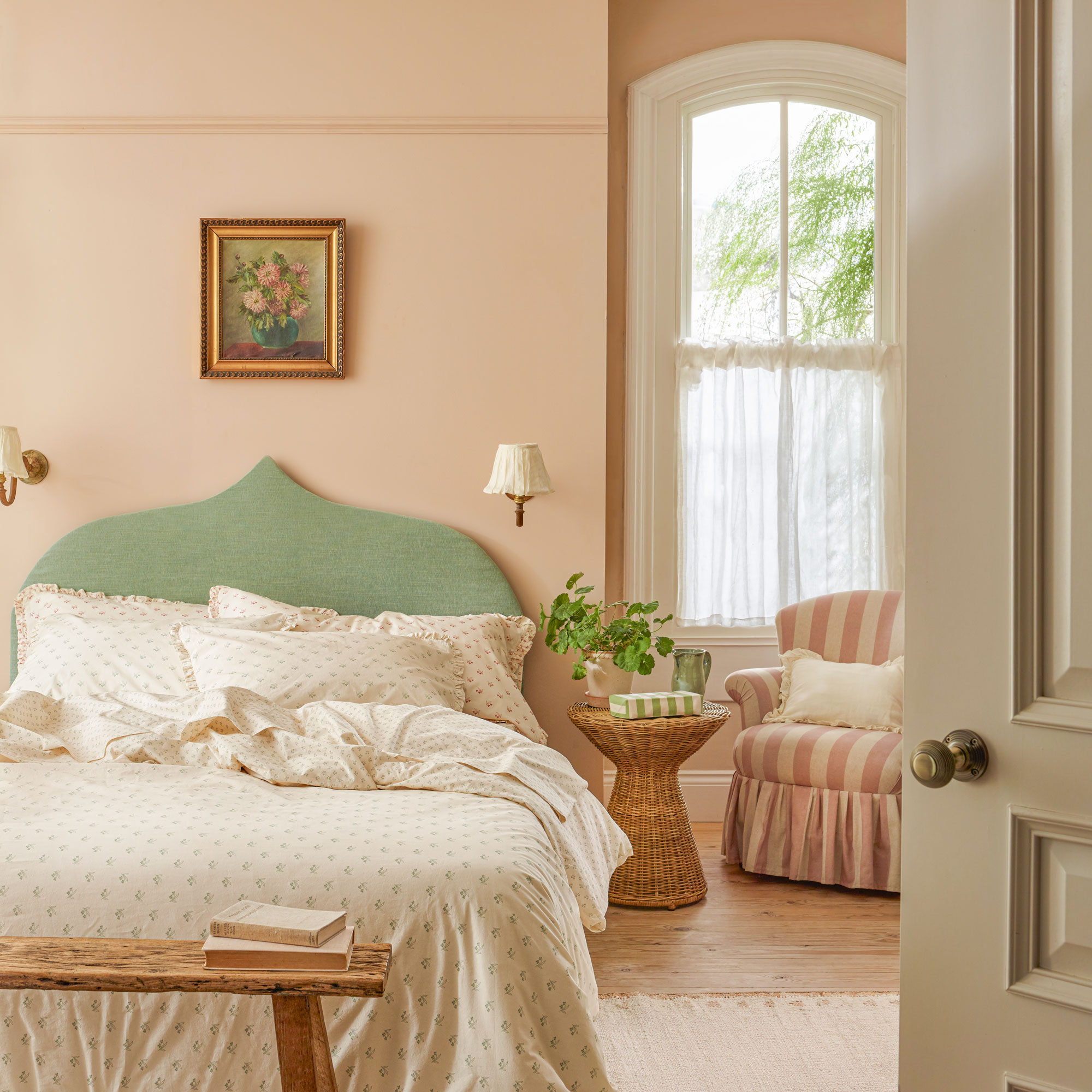 Pink bedroom with a green bed and wall lights