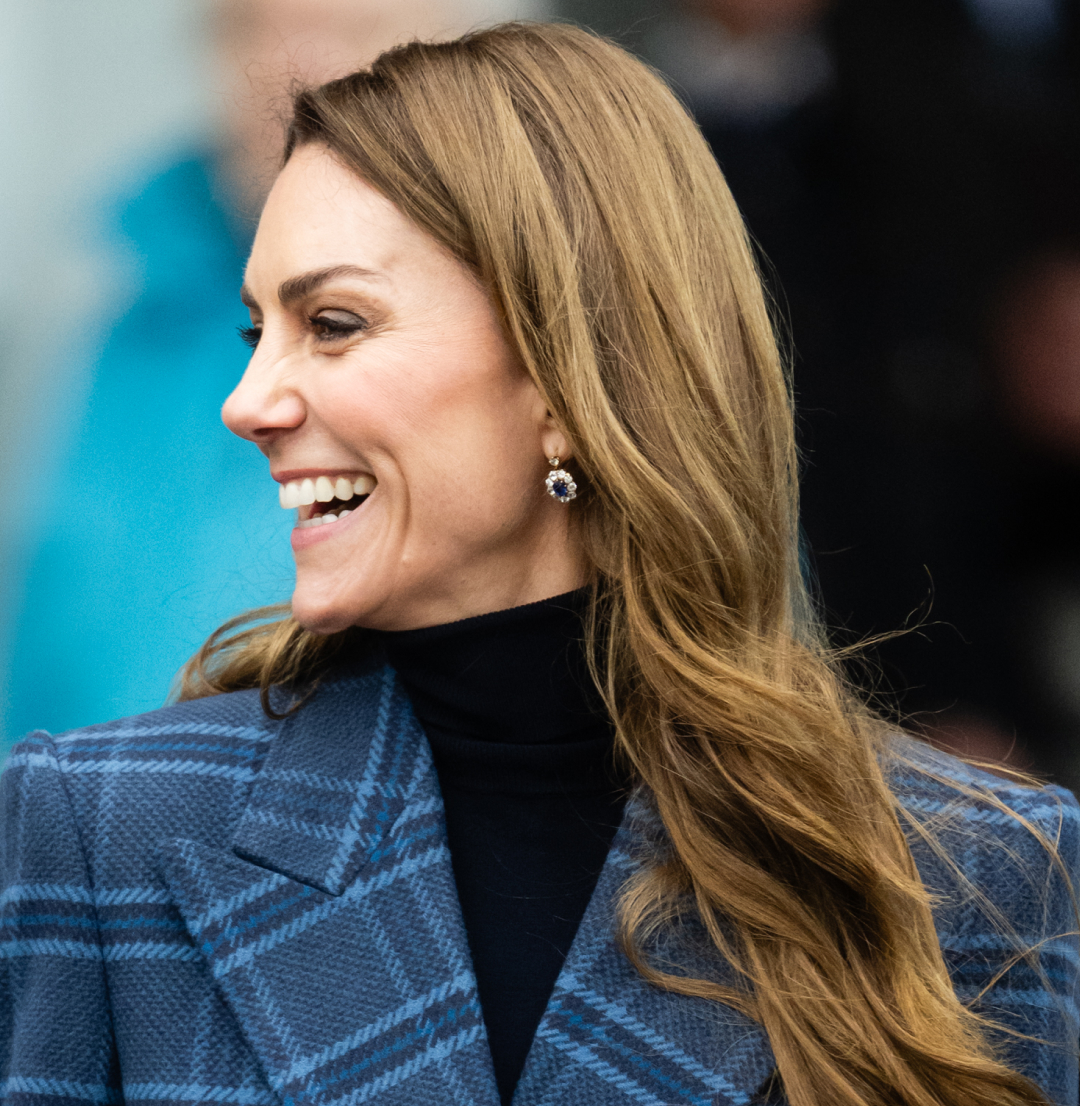 Kate Middleton wearing a blue plaid coat and smiling