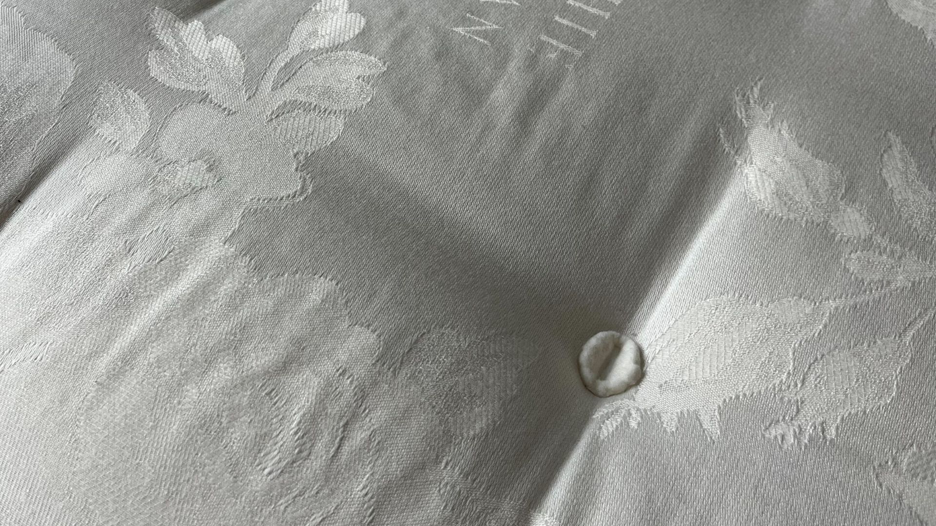 close up of the top of the mattress with button and design visible