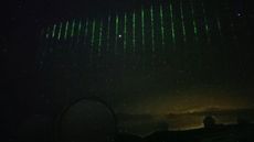 A time-lapse image of the green laser pulses flashing across the night sky.