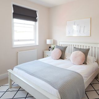 bedroom with pink wall frame on wall and white bed with pink and designed pillows