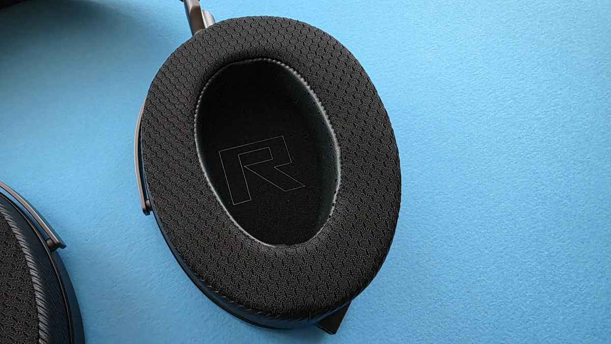 A pair of large, black, over-ear headphones with a striped grille design rests on a blue surface.