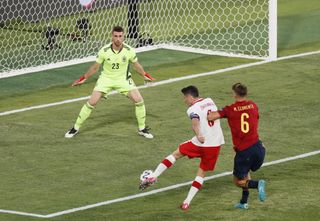 Poland’s Robert Lewandowski (centre) shots for goal against Spain