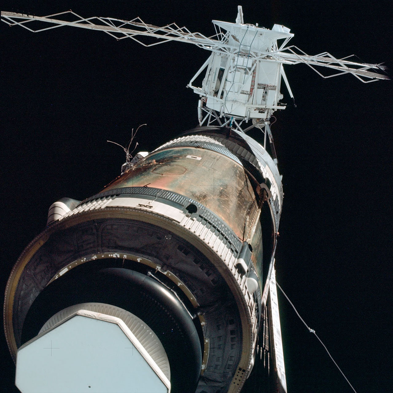 The Skylab orbital workshop in its post-launch, damaged condition, as photographed by the Skylab 2 crew. Frayed wires can be seen protruding where one of the space station's two solar arrays had been torn off with a micrometeoroid shield and sun shade.