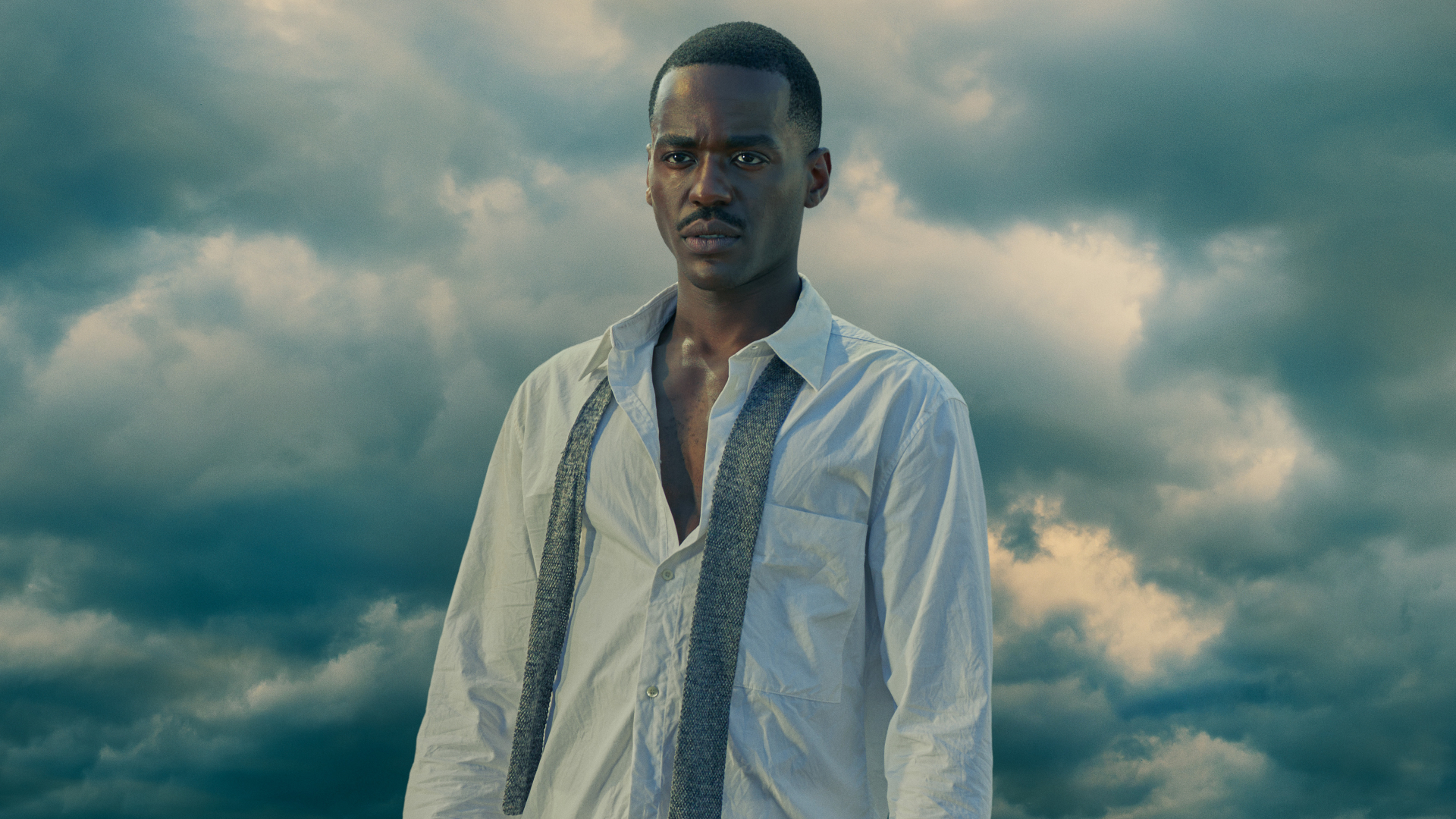 Ncuti Gatwa stands in an unbottoned white shirt with a tie in Doctor Who