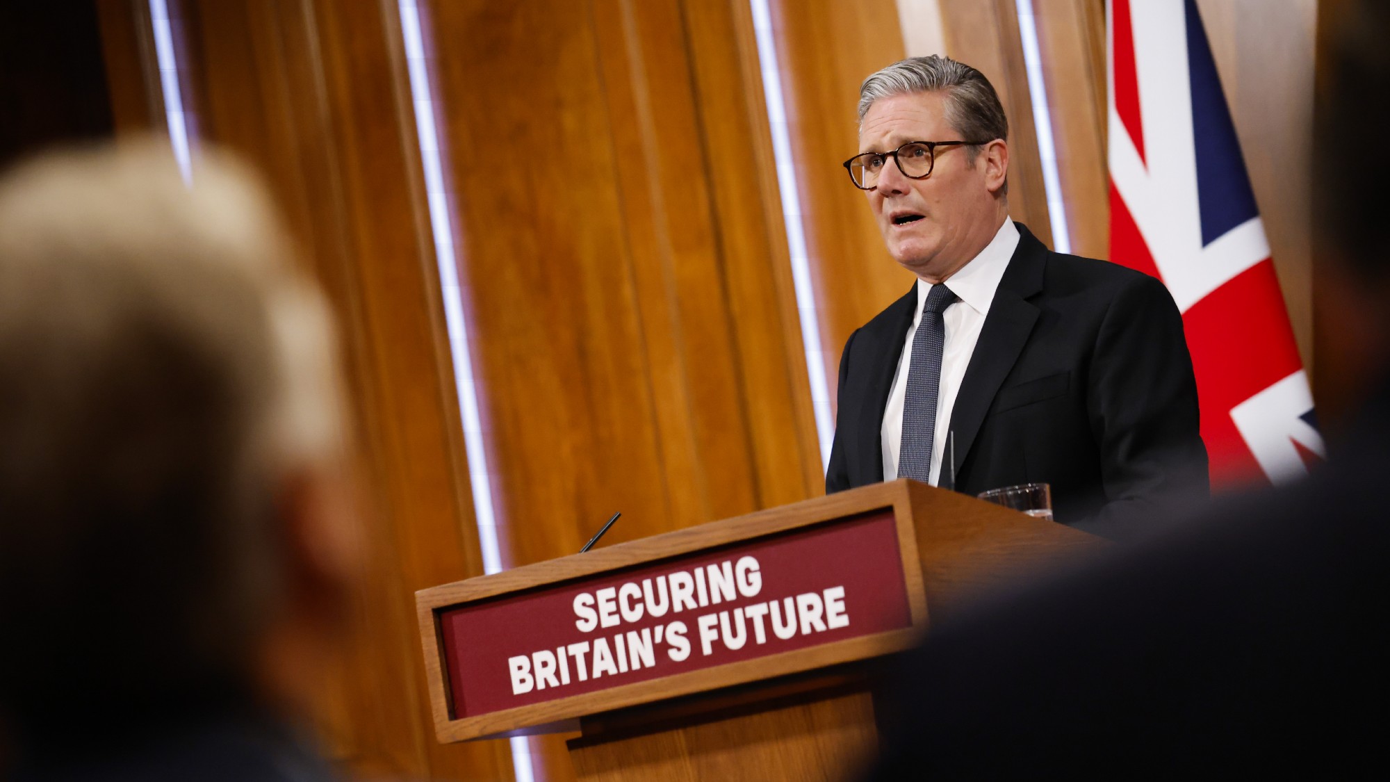 Keir Starmer at a podium labelled "securing Britain's future" during a news conference ahead of the publication of the government's immigration white paper