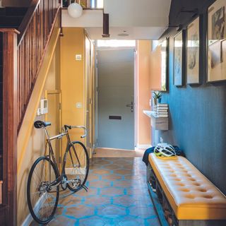 Hallway with yellow paint on one wall and blue paint on the other with bike propped up.