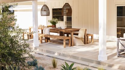 covered outdoor dining area with table and benches, hanging lanterns and accessories, with gravel landscaping and planting