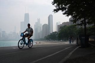 Man riding a bike on a road with smog in the air.