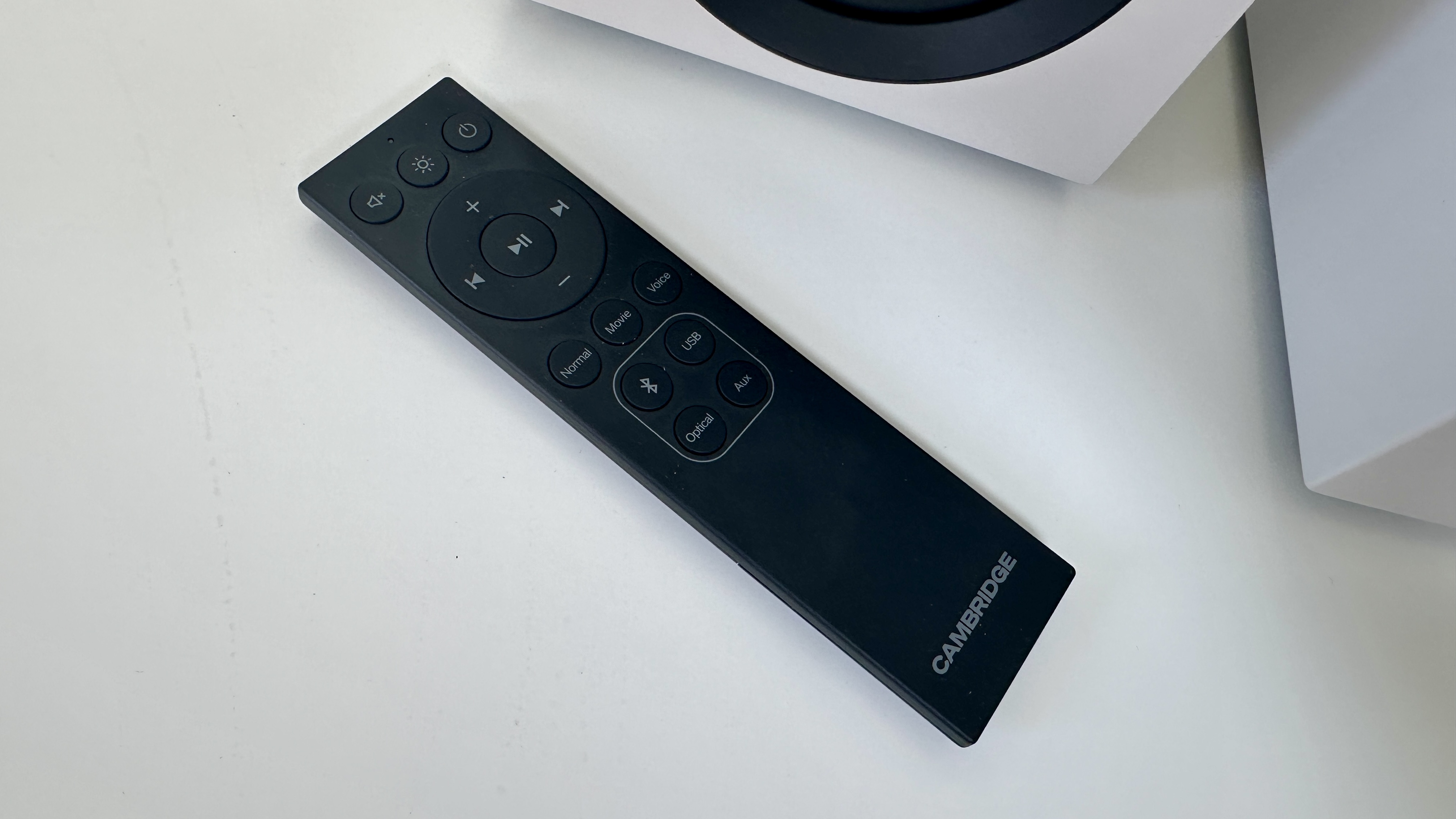 Remote control for the Cambridge L/R S active speaker system, on a white surface.