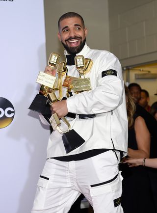 Drake smiling at 2017 Billboard Music Awards with many trophies
