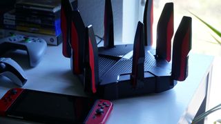TP-Link Archer GX90 gaming router on a table near video games