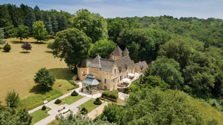 an aerial view of stone chateau with manicured garden