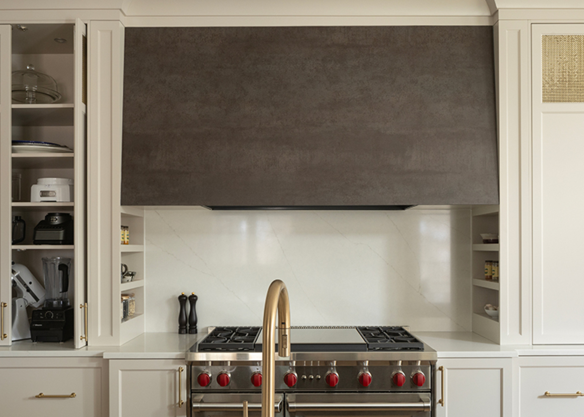 An range oven in a built-in alcove with a rustic metal hood and niche shelving either side