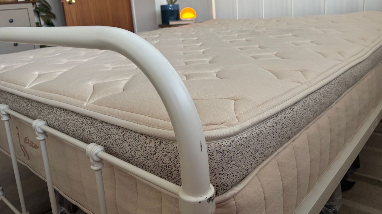 The beige Birch Elite Natural mattress placed on a white bedframe inside a mattress tester's neutrally decorated bedroom