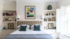 A picture of a white bedroom with a bed with a buttoned headboard, bookcase with books and pictures and an open window to the right to support advice for the things you should declutter in 2024 