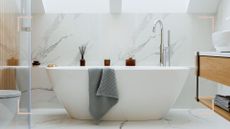 White bathroom with freestanding bath and marble wall panels to avoid common bathroom design mistakes 