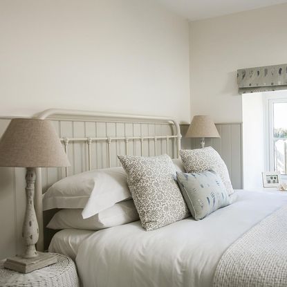 bedroom with white wall and pillows on bed with table lamp