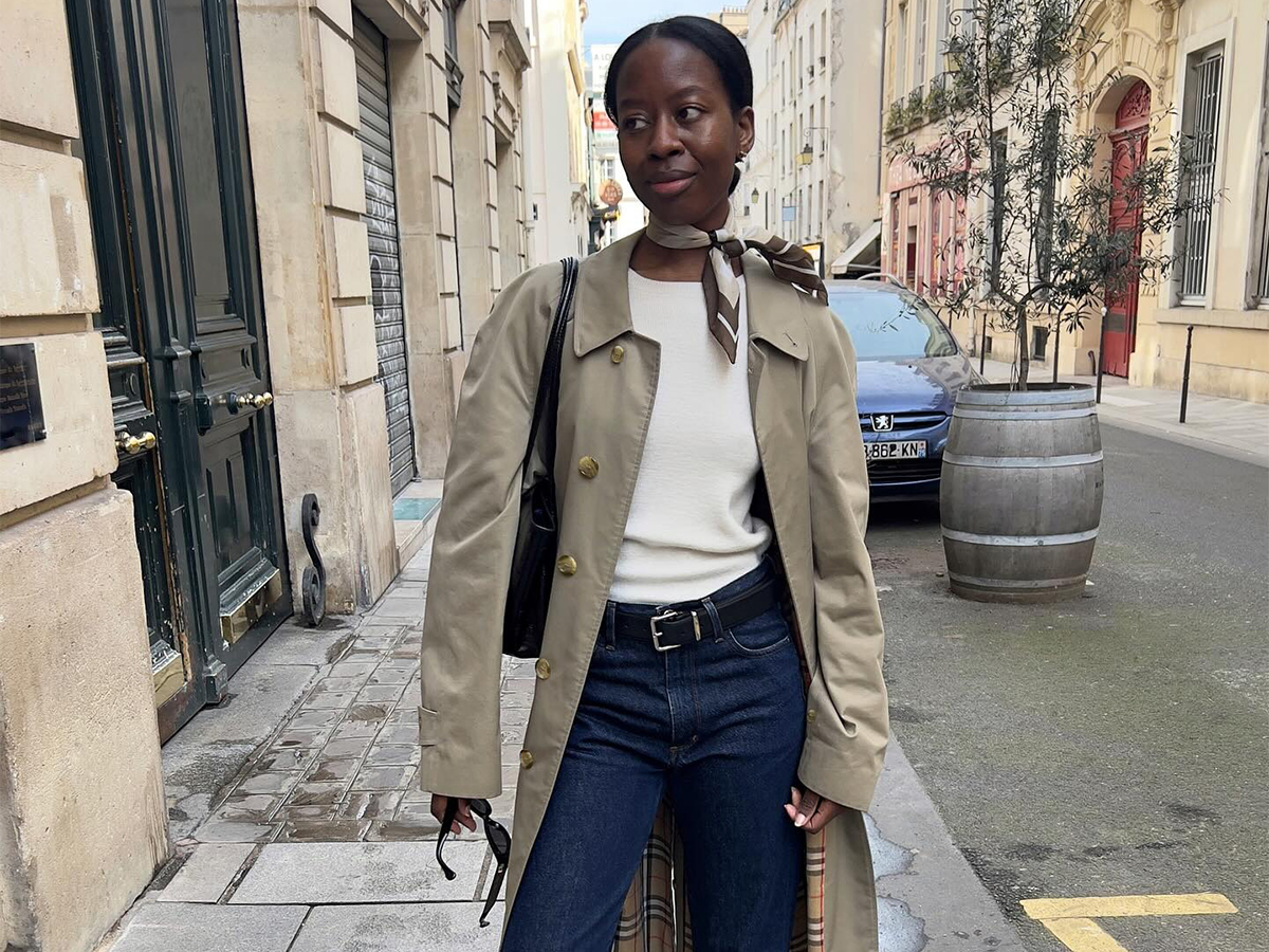 Influencer Sylvie Mus wears dark wash jeans, white tee, trench coat, and scarf.