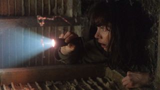 Lorna Brady with flashlight in a crawlspace in The Woman in the Wall episode 6